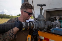 U.S. Marine Corps Lance Cpl. Robert Byers, an expeditionary fuels technician with Marine Wing Support Squadron 171, Marine Aircraft Group 12, 1st Marine Aircraft Wing, attaches a fuel hose to a fuel truck during an Aviation Training Relocation program at Tinian, Northern Mariana Islands, January 16, 2026.