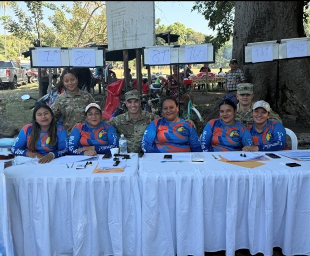 Soldiers and civilians sit side by side at a table.
