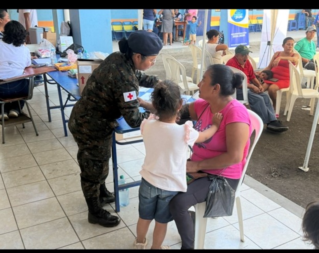 A medic in a military uniform renders aid to another person