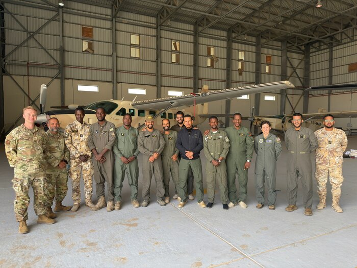 A group of military members pose for a photo in front of a building.