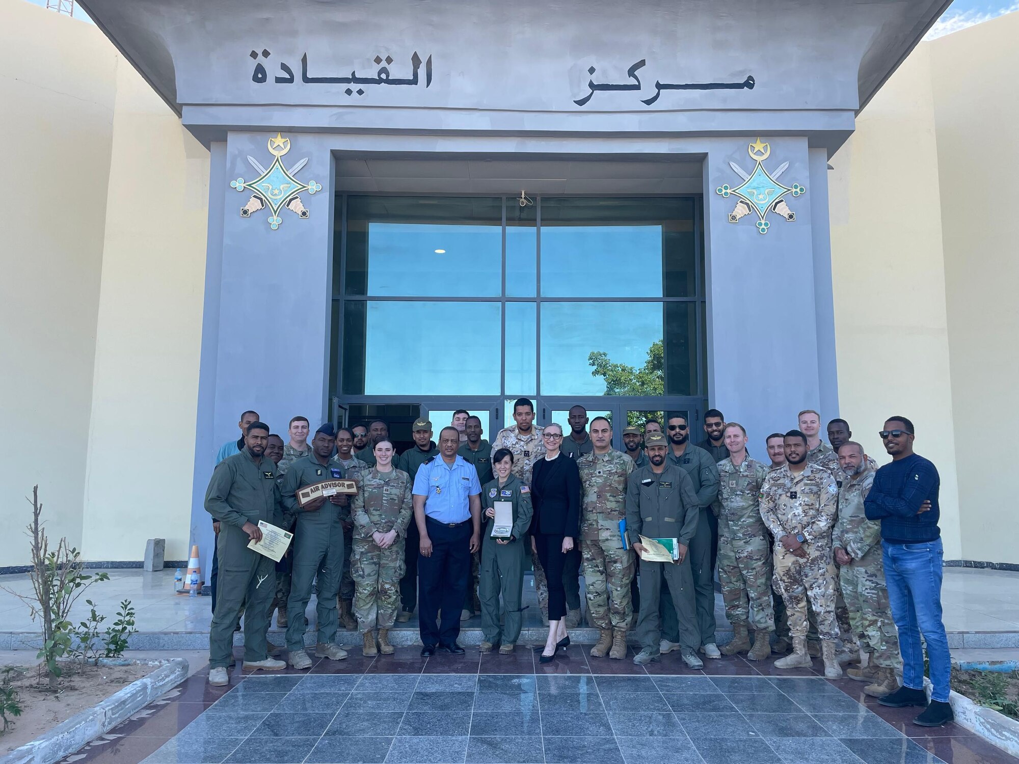 A group of military members pose for a photo in front of a building.