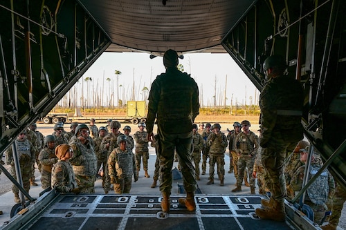 A woman addresses a crowd outside of a plane.