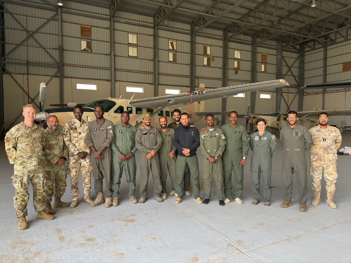 A group of military members pose for a photo in front of a building.