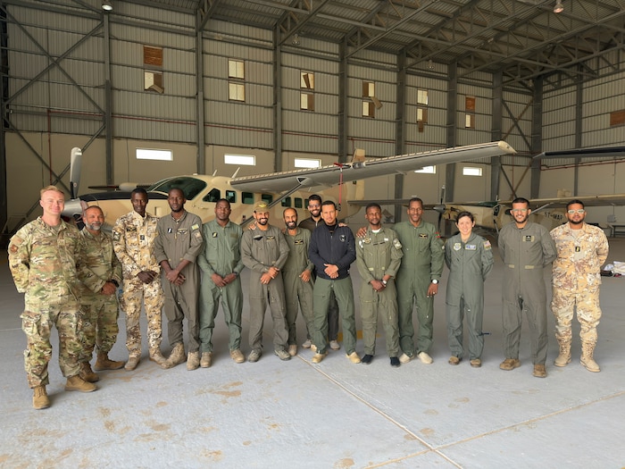 A group of military members pose for a photo in front of a building.