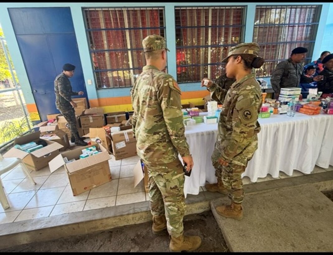 Soldiers in military uniforms go through boxes of medical supplies.