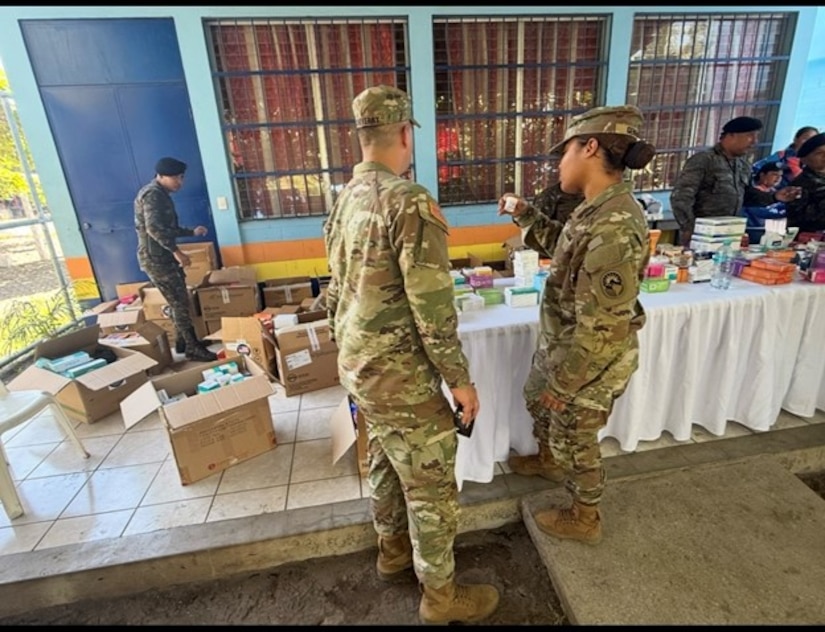 Soldiers in military uniforms go through boxes of medical supplies.