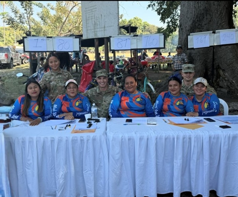 Soldiers and civilians sit side by side at a table.