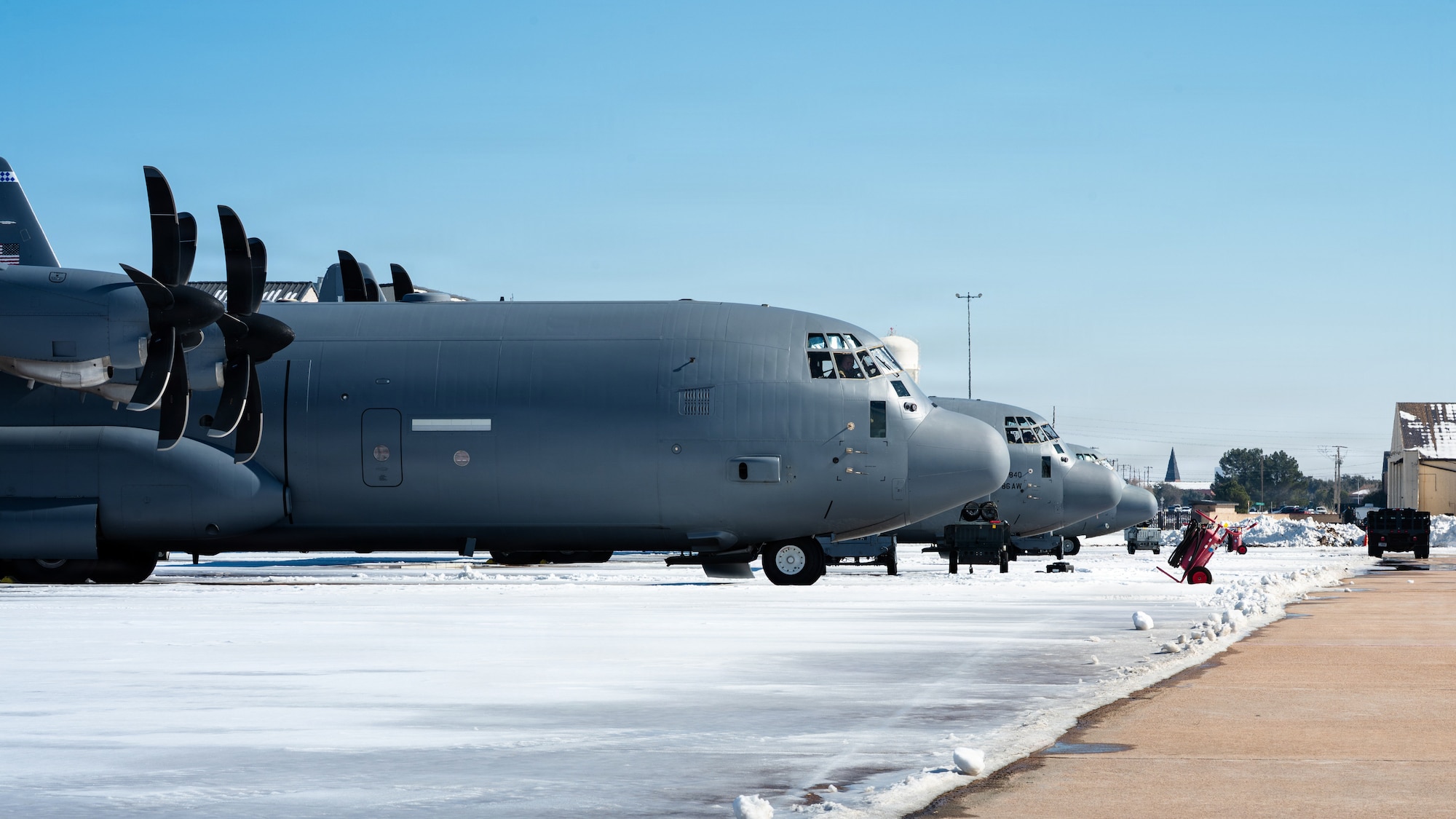 U.S. Air Force C-130J Super Hercules aircraft prepare to depart after Winter Storm Fern at Dyess Air Force Base, Texas, Jan. 28, 2026. The 7th Civil Engineer Squadron prepared to open the airfield for C-130J operations days in advance without organic snow removal equipment. The 7th CES relied on a loader fitted with a box blade, one excavator, one backhoe and two rented ten-foot road construction sweepers. (U.S. Air Force photo by Senior Airman Jade M. Caldwell)