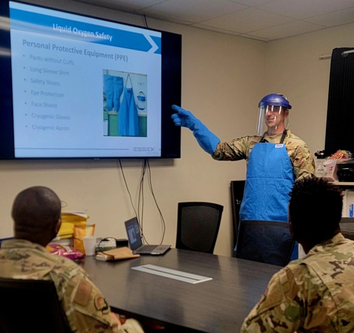 Image of an Airman training with other people, pointing at a screen.