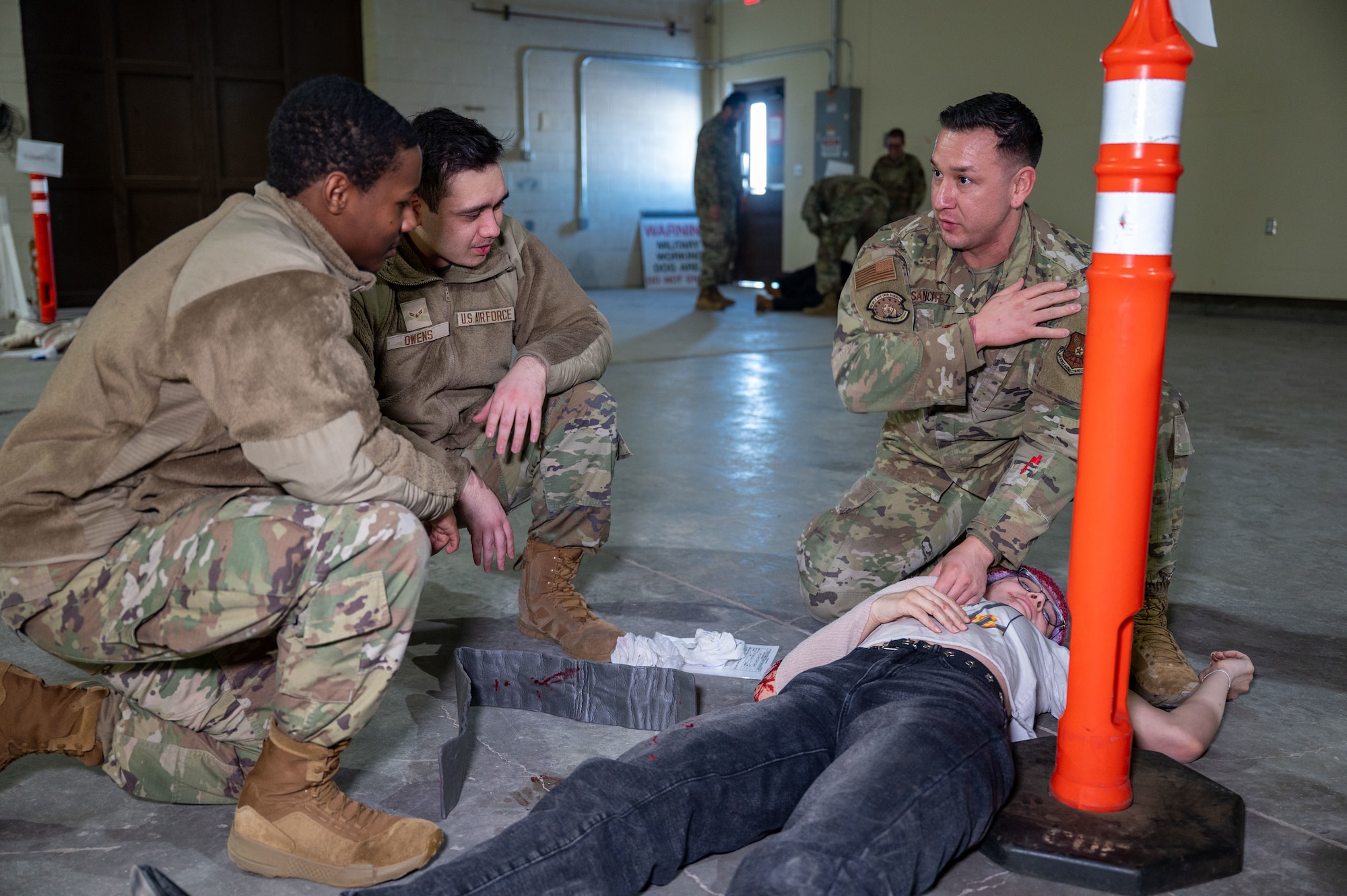 Three men in uniform around a simulated injured woman