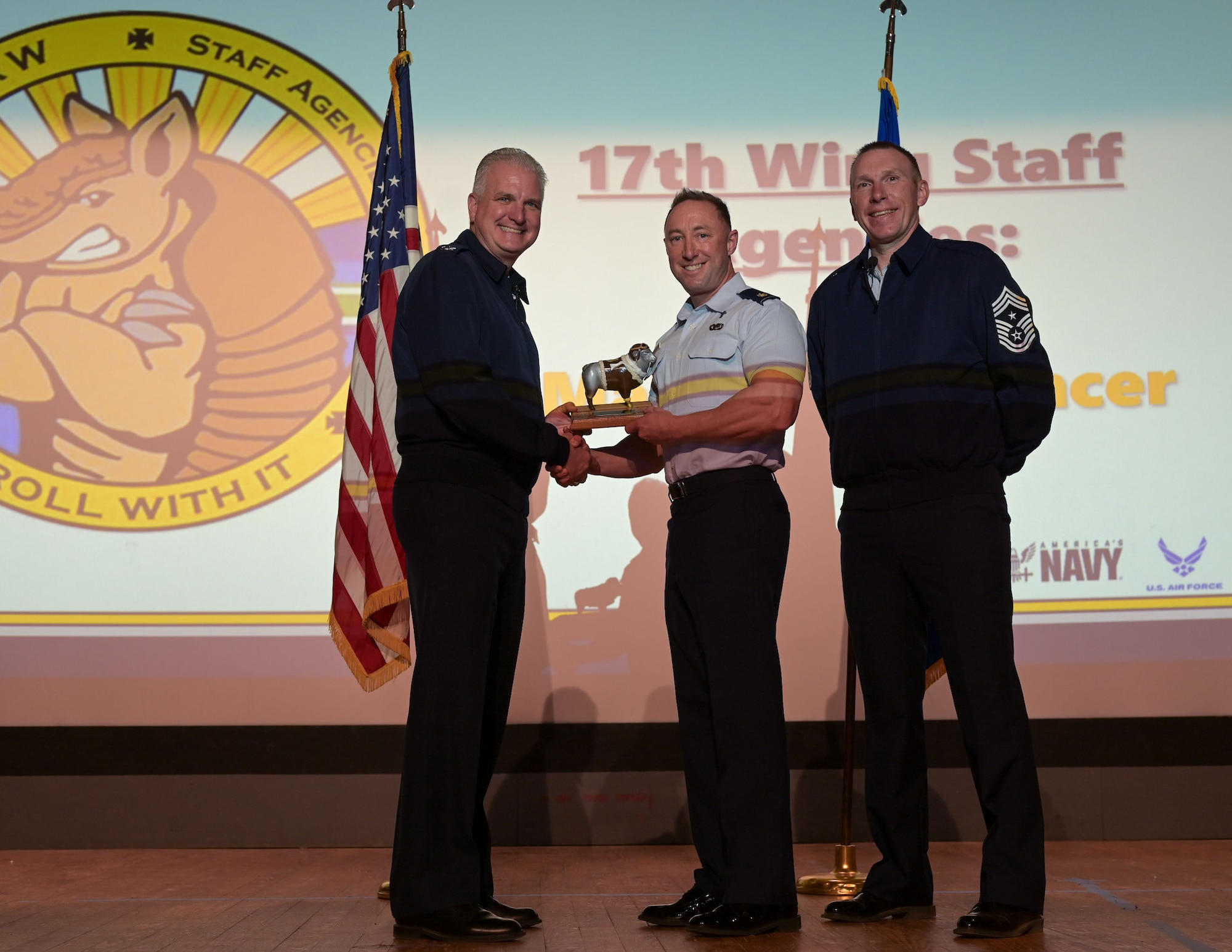 U.S. Air Force Maj. Larry Spencer, center, 17th Training Wing Chapel chaplain, receives the 17th Training Wing Field Grade Officer of the Quarter award from Col. Matthew Norton, left, 17th TRW commander, Chief Master Sgt. Derek Neil, right, 17th TRW command chief, during the 17th TRW All-Call and 4th Quarter Awards Ceremony at the base theater, Goodfellow Air Force Base, Texas, Jan. 30, 2026. The 17th Chapel Team exists to support the religious, spiritual and moral well-being of Airmen, Guardians, and their families. (U.S. Air Force photo by Senior Airman Evelyn J. D'Errico)
