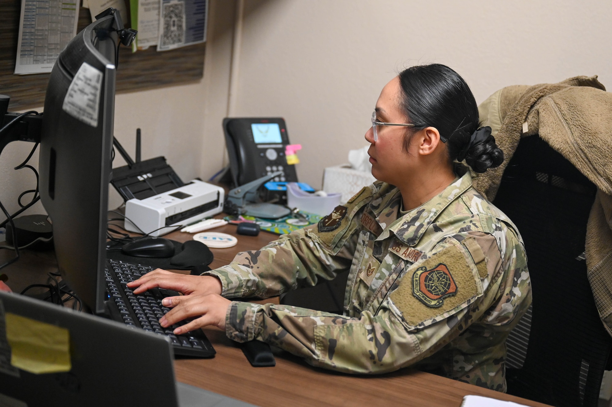 Woman sits at desk and types at computer.