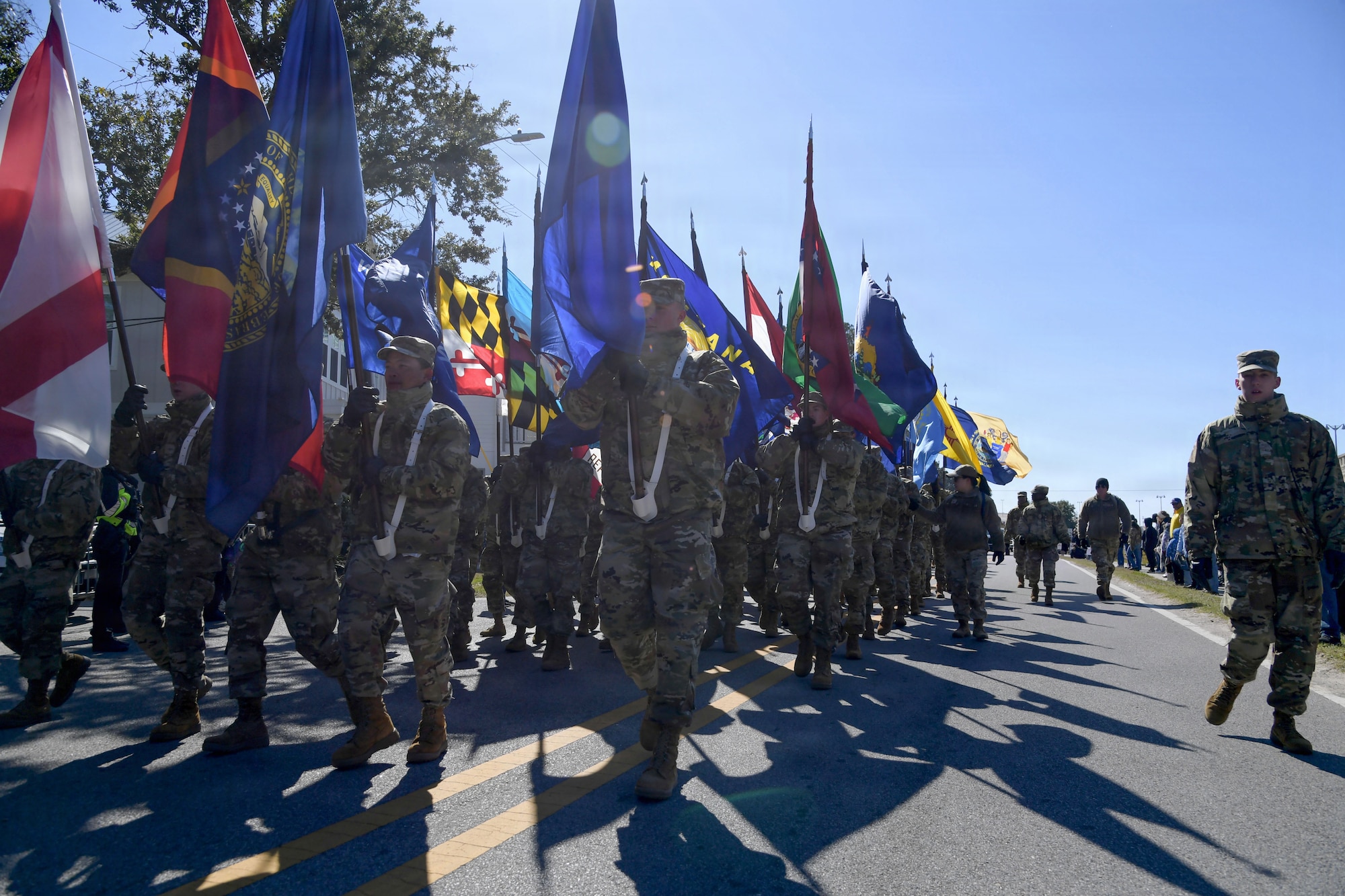 U.S. Airmen in military uniforms walk through the streets carrying the U.S. State Flags.