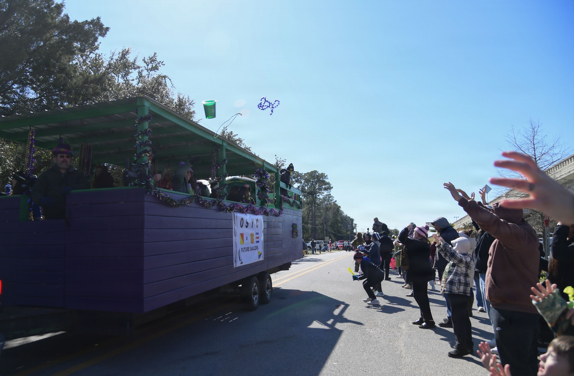 People throw beads from a float to a crowd