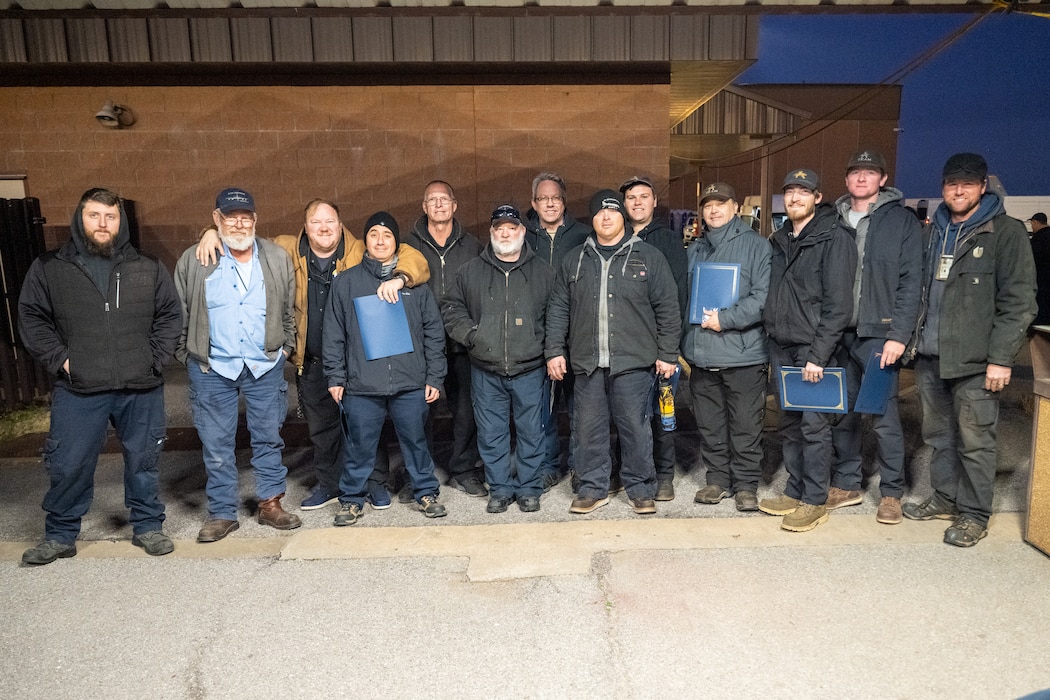 U.S. Air Force 97th Aircraft Maintenance Squadron (AMXS) maintainers stand next to AMXS leadership at Altus Air Force Base, Oklahoma, Jan. 22, 2026. The maintainers were given Knuckle Buster awards for performing above-standard field work on repairing a KC-135 Stratotanker aircraft trunnion, a critical part of the landing gear. (U.S. Air Force photo by Airman 1st Class Nathan Langston)