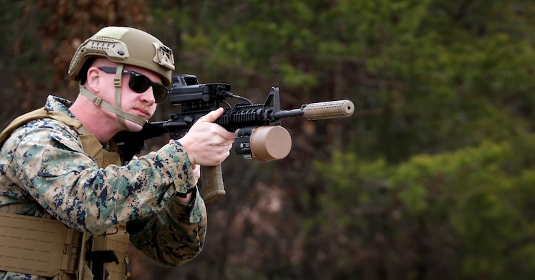Marine pointing a rifle using the Organic Counter Small UAS equipment integrated on top of the rifle