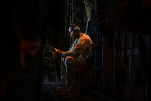 man sitting in dark with red light illuminating him
