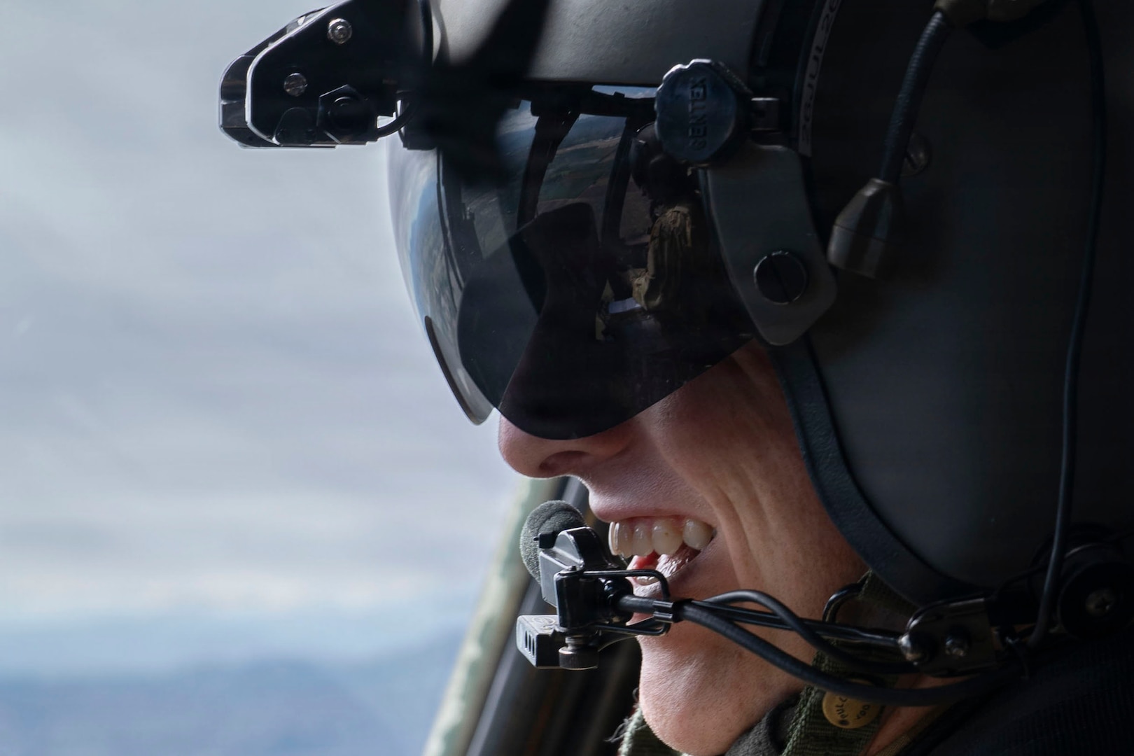 A man smiles while wearing a military aviation helmet