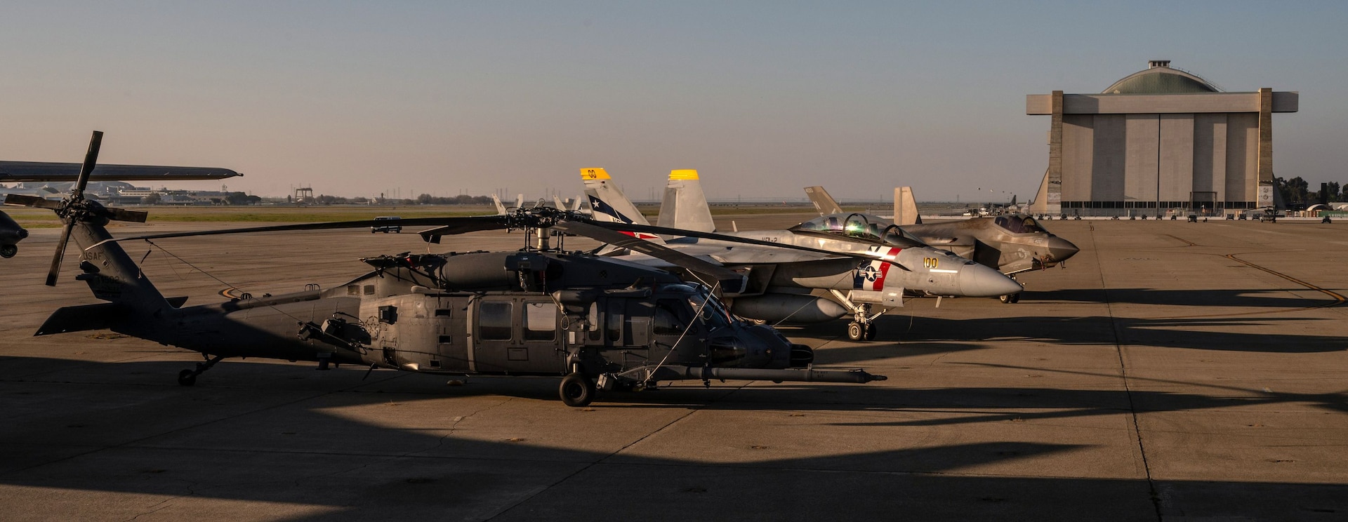 129th Rescue Wing stationed at Moffett Air National Guard Base is on the ramp, Feb. 4, while the base hosts Super Bowl LX flyover aircraft including a U.S. Navy F/A-18F Super Hornet from Strike Fighter Squadron 2 (VFA-2) and a Navy F-35C Lightning II from Strike Fighter Squadron 97 (VFA-97).