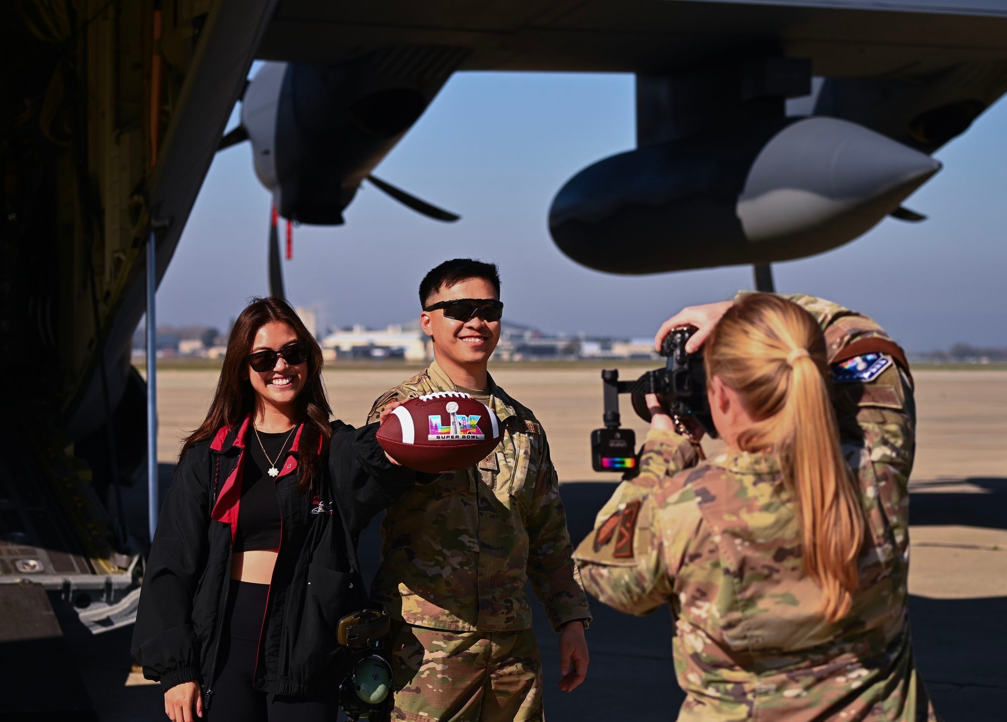 U.S. Air Force Staff Sgt. King Hey Leung from the 129th Maintenance Squadron, 129th Rescue Wing, and his wife, Crisly, shoot a social media clip during a Super Bowl LX military flyover outreach event, Feb. 5, on Moffett Air National Guard Base, Calif.
