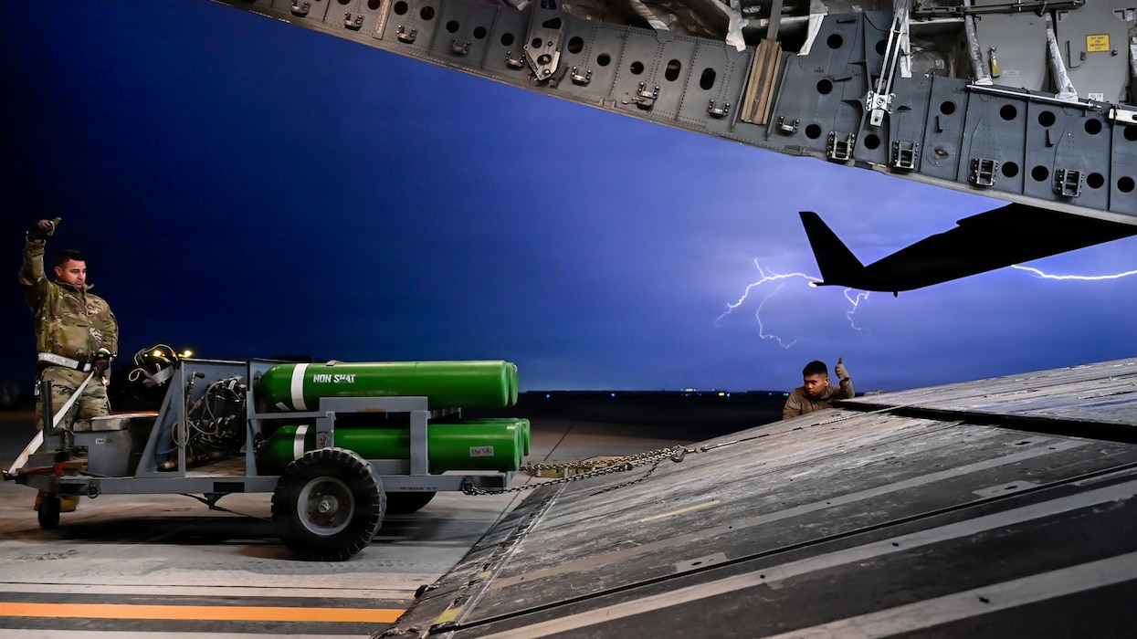 Airman loading cargo into C-17 during lightning storm