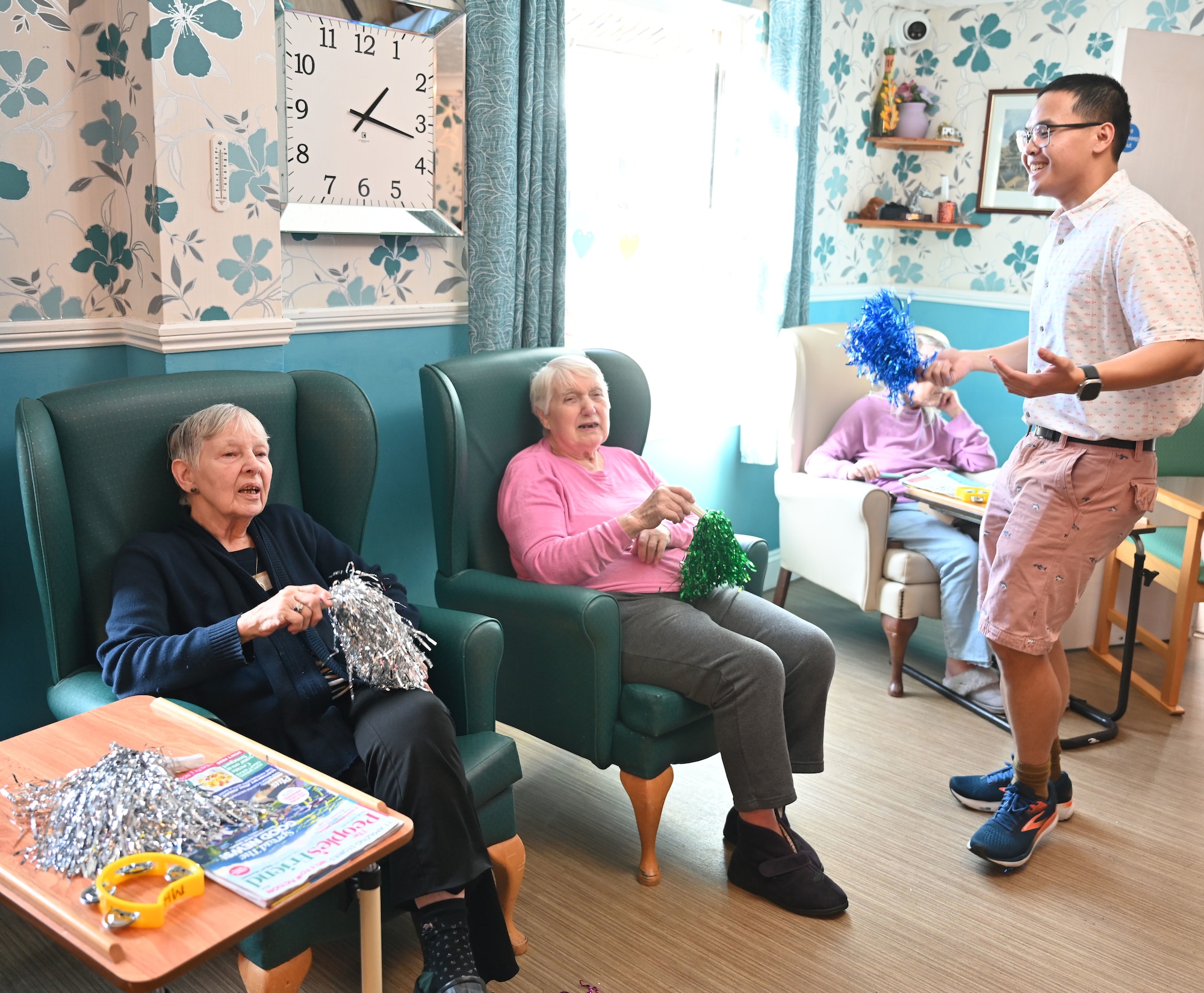 U.S. Air Force Airman 1st Class Julius Del Rosario, 100th Communications Squadron, sings and dances with residents at Mabbs Hall Care Home, Mildenhall, England, Jan. 28, 2026. Airmen with the RAF Mildenhall Top 3, 100th Civil Engineer Squadron and 100th CS  visited the local care home to spend time with and entertain residents with karaoke. (U.S. Air Force photo by Karen Abeyasekere)