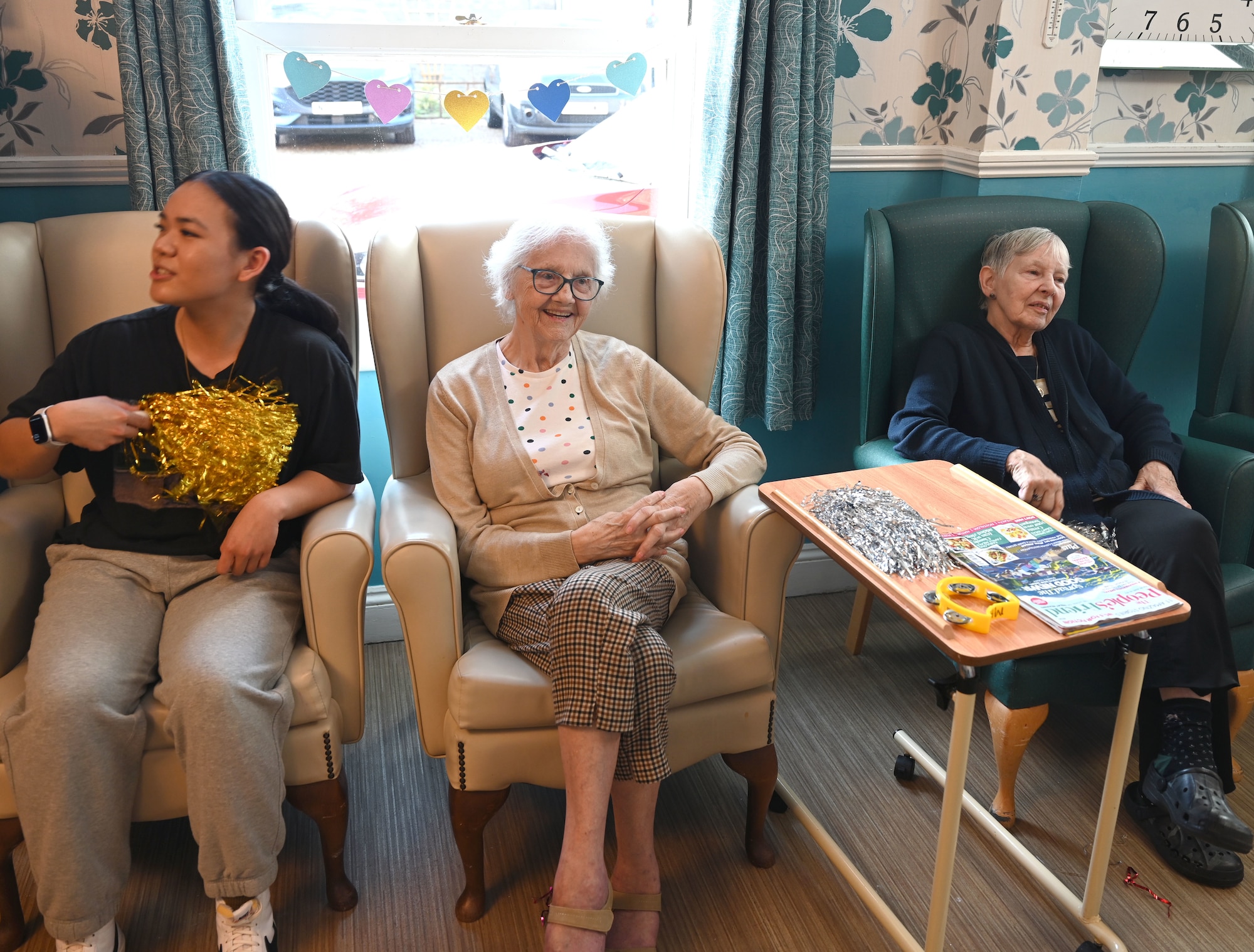 U.S. Air Force Senior Airman Angeryll Tipay, left, 100th Civil Engineer Squadron, sings along with residents at Mabbs Hall Care Home, Mildenhall, England, Jan. 28, 2026. Airmen with the RAF Mildenhall Top 3, 100th CES and 100th Communications Squadron visited the local care home to spend time with and sing karaoke with the residents. (U.S. Air Force photo by Karen Abeyasekere)