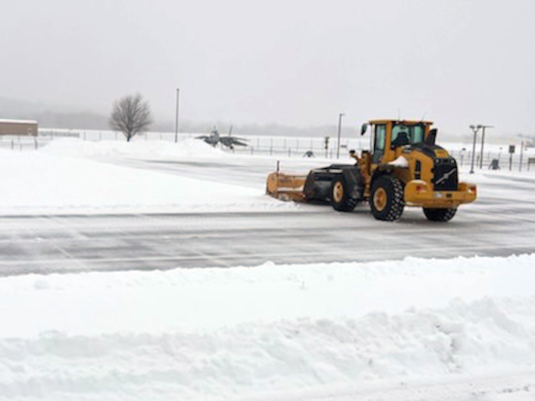 A snowplow clears a snowy and icy road.