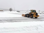 A snowplow clears a snowy and icy road.