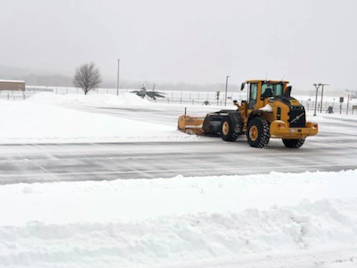 A snowplow clears a snowy and icy road.