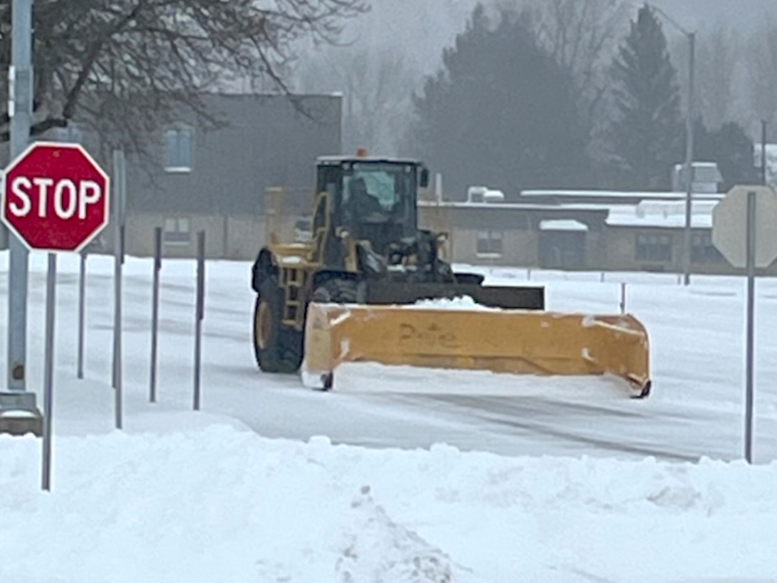 A snowplow clears a snow-covered road.