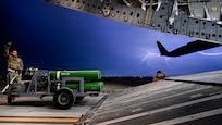 Airman loading cargo into C-17 during lightning storm