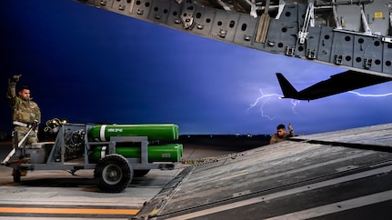 Airman loading cargo into C-17 during lightning storm