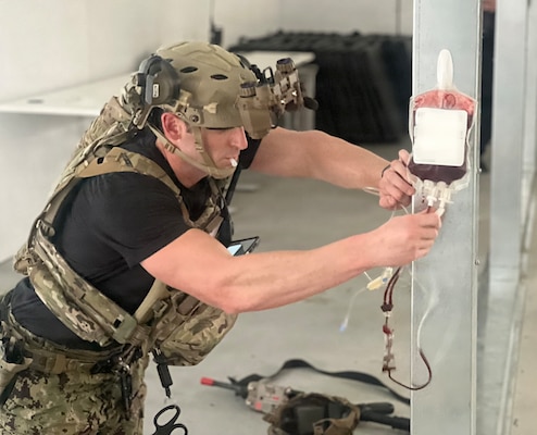 FORT BELVOIR, Va. (Jan. 23, 2026) Lt. Cmdr. Josh Kotler, assigned to Navy Medicine Readiness and Training Command (NMRTC) Fort Belvoir, prepares a unit of emergency fresh whole blood for transfusion on volunteer simulated patient during NMRTC Fort Belvoir hosted Joint Trauma System (JTS) Valkyrie Course, Jan. 23, 2026. The training prepares teams to run Emergency Fresh Whole Blood Transfusion (EFWBT) programs in large-scale combat and austere environments. (U.S. Navy photo by Hospital Corpsman 3rd Class Briana Baxter) (This photo was altered for security purposes by blurring out identification badges.)