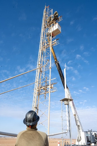 U.S. Air Force Senior Airman Gregory Curry, 332nd Expeditionary Civil Engineer Squadron electrical journeyman, supervises Airmen from the Air Forces Central Deployed Regional Maintenance Center while they adjust antennae heights on a glide slope.