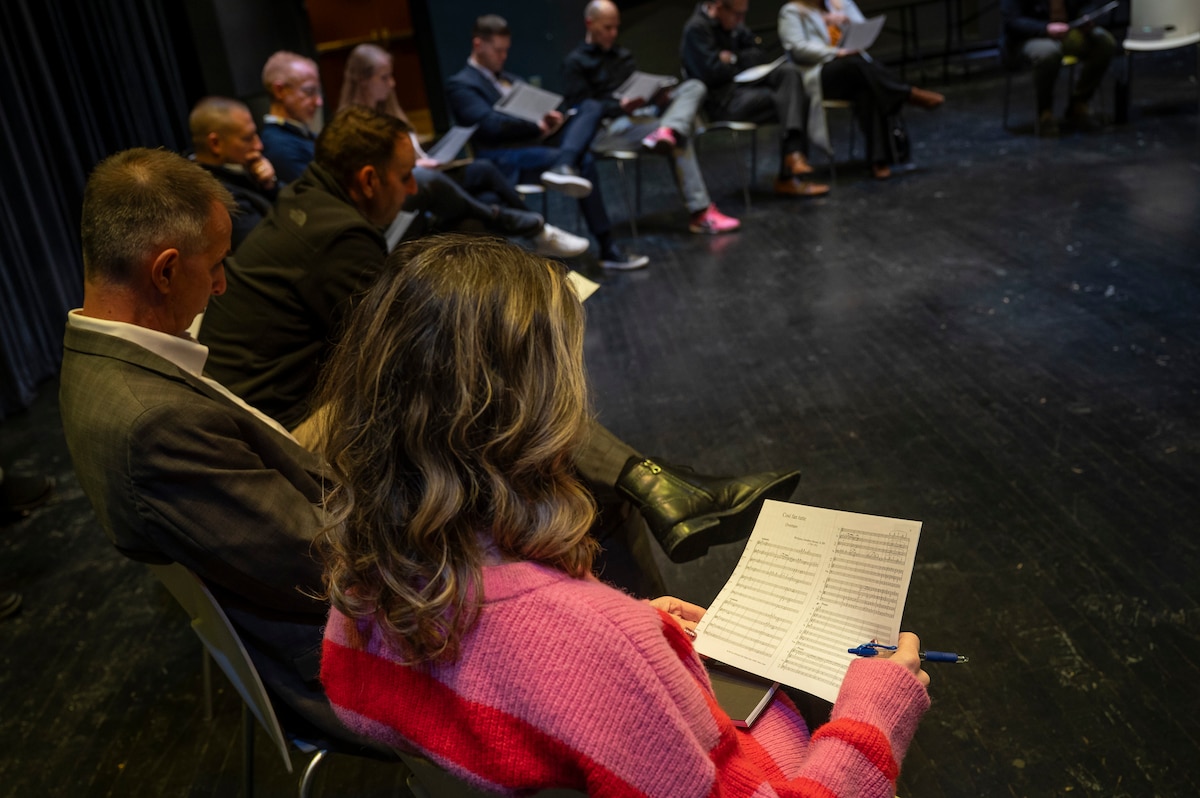 Closeup of professionals sitting in a circle and looking at sheet music.