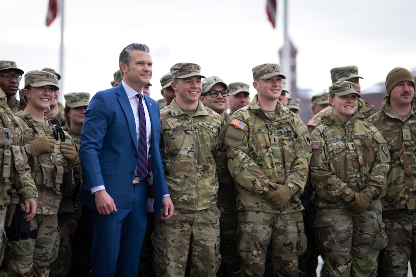 The secretary of war poses for a photo with dozens of troops.
