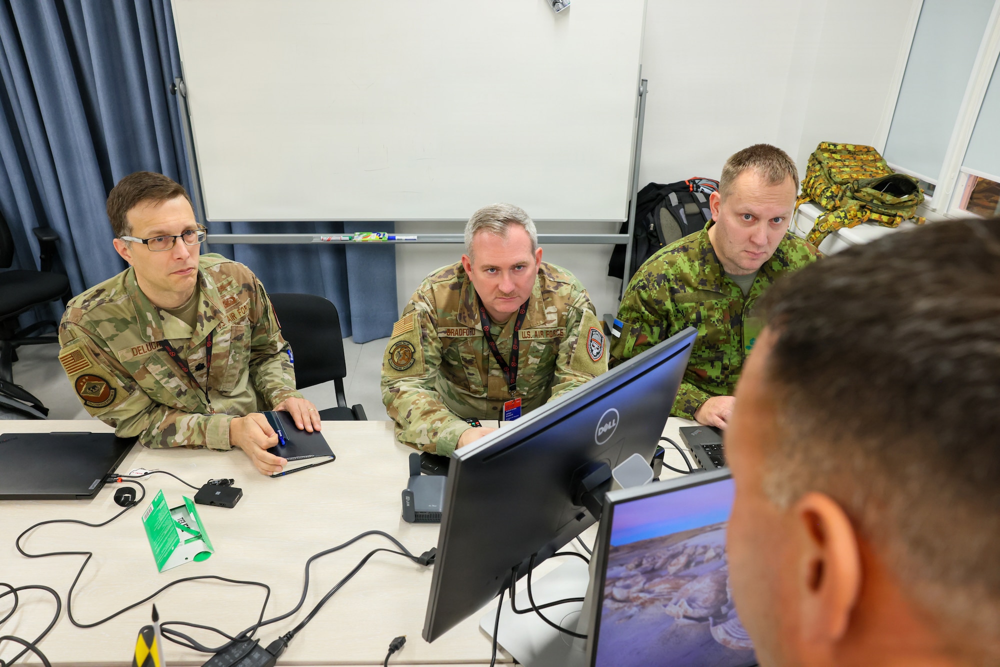 Maryland Air National Guard Lt. Col. Bob DeLuca, flight commander for the 175th Cyberspace Operations Squadron, Capt. James Bradford with the 276th Cyberspace Operations Squadron, and a member of the Estonian Defence Force speak with Maryland Air National Guard Senior Master Sgt. Martin Bartkowski, 275th Operations Support Squadron cyber intelligence analyst, participate in Crossed Swords 25 in Tallinn, Estonia, November 3, 2025. The exercise hosted 240 participants from about 45 countries and participants shared tactics and procedures to contribute towards a cohesive collective-defense strategy. (Courtesy Photo)