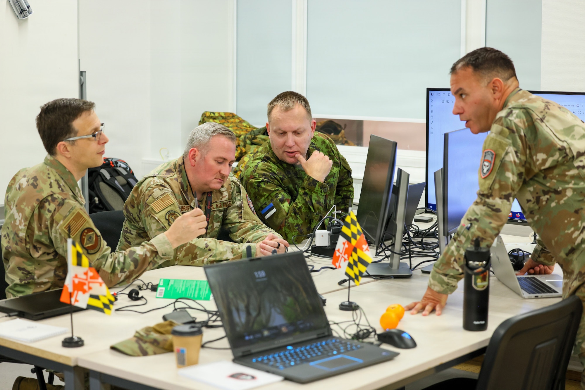 Maryland Air National Guard Lt. Col. Bob DeLuca, flight commander for the 175th Cyberspace Operations Squadron, Capt. James Bradford with the 276th Cyberspace Operations Squadron, and a member of the Estonian Defence Force speak with Maryland Air National Guard Senior Master Sgt. Martin Bartkowski, 275th Operations Support Squadron cyber intelligence analyst, participate in Crossed Swords 25 in Tallinn, Estonia, November 3, 2025. The exercise hosted 240 participants from about 45 countries and participants shared tactics and procedures to contribute towards a cohesive collective-defense strategy. (Courtesy Photo)