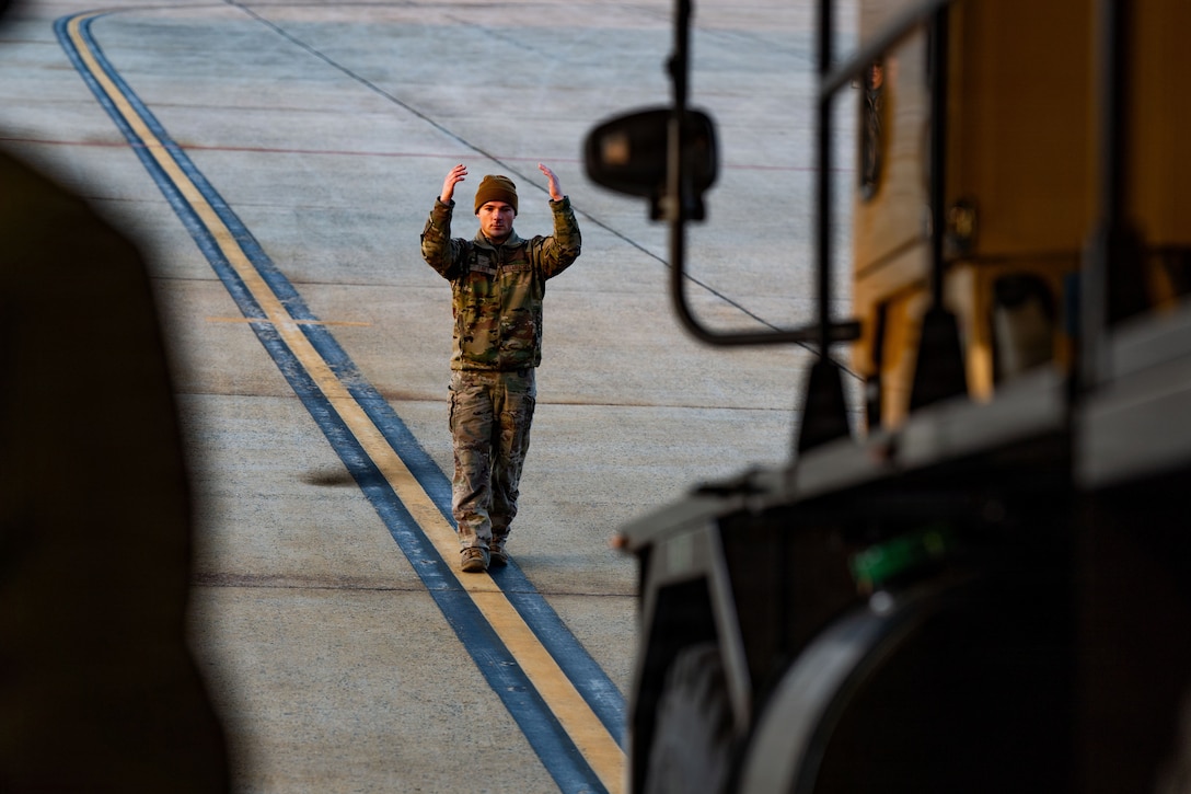 U.S. Air Force Senior Airman Jason Davey, 6th Airlift Squadron C-17 Globemaster III loadmaster, Joint Base McGuire Dix Lakehurst, N.J., marshals a heavy snow plow off a C-17 at Joint Base Andrews, Md., Jan. 23, 2026. Air Mobility Command mobilized mission-ready Airmen and specialized equipment in support of winter weather preparedness efforts to ensure “America’s Airfield” remained operational amid historic severe weather impacts. (U.S. Air Force photo by 1st Lt. Alexis Kula)