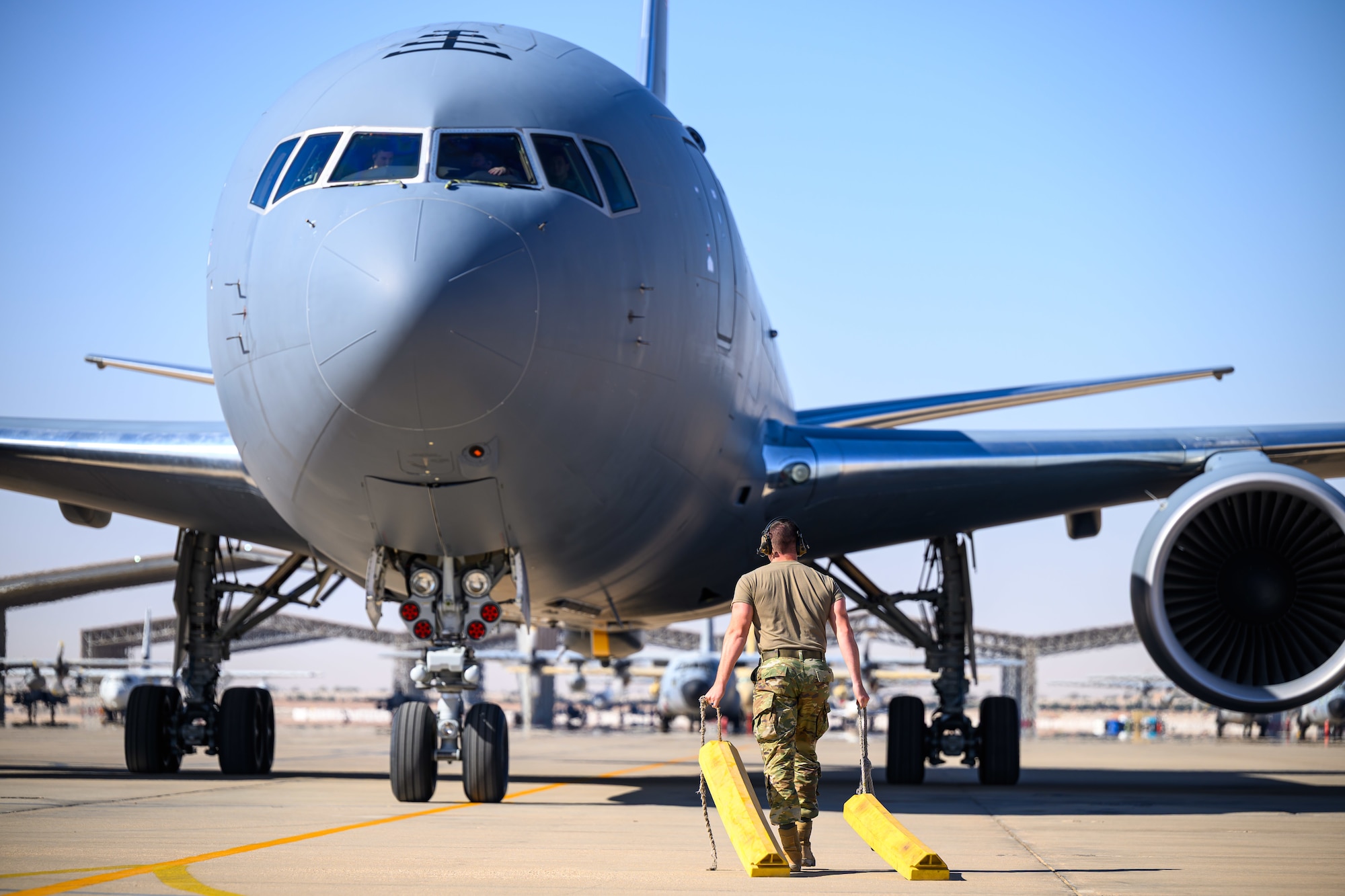 U.S. Air Force Senior Airman Tyler Feigh, 378th Expeditionary Maintenance Squadron transient alert journeyman, chocks a KC-46A Pegasus aircraft assigned to the 77th Expeditionary Air Refueling Squadron in the U.S. Central Command area of responsibility.