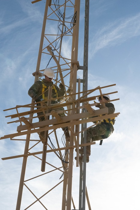 U.S. Air Force Tech. Sgt. Keenan Herlocker, Air Forces Central Deployed Regional Maintenance Center noncommissioned officer in charge, left, and Staff Sgt. Jessica Ayala, AFCENT DRMC production control noncommissioned officer in charge, right, adjust antennae heights on a glide slope in the U.S. Central Command area of responsibility Feb. 5, 2026. The system gives pilots reliable guidance to established touchdown points when the runway is not visually acquired. (U.S. Air Force photo by Senior Airman Kari Degraffenreed)