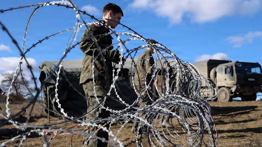 Polish Armed Forces Soldiers, assigned to 1st Missile Brigade, set up concertina wire around the perimeter of the command post during Dynamic Front 26, Feb. 06, 2026, in Cincu, Romania
