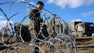 Polish Armed Forces Soldiers, assigned to 1st Missile Brigade, set up concertina wire around the perimeter of the command post during Dynamic Front 26, Feb. 06, 2026, in Cincu, Romania
