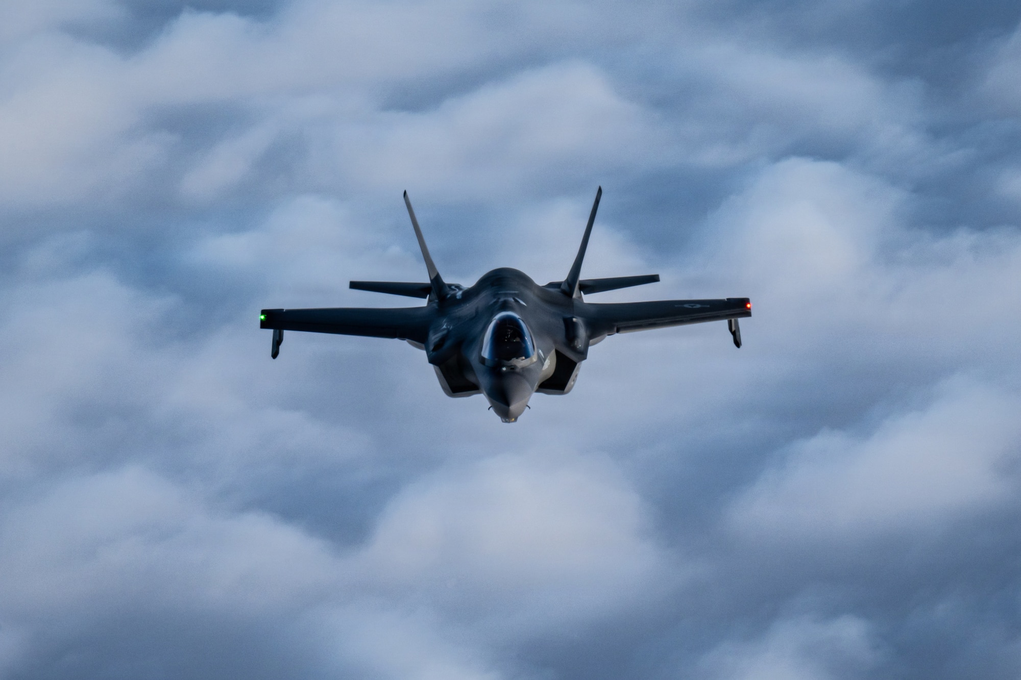 A U.S. Air Force F-35 Lightning II flies above a cloud bank on approach to receive fuel