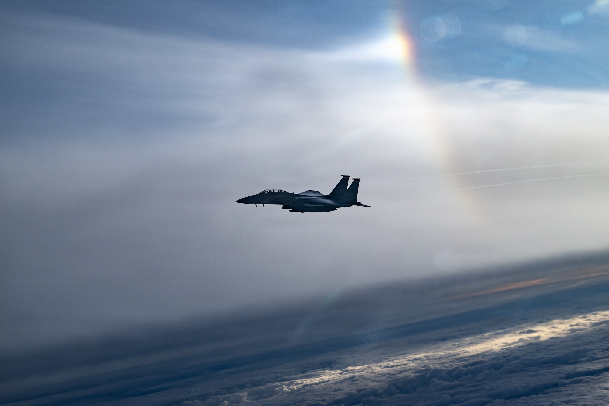 A U.S. Air Force F-15E Strike Eagle flies in the sky in front of clouds