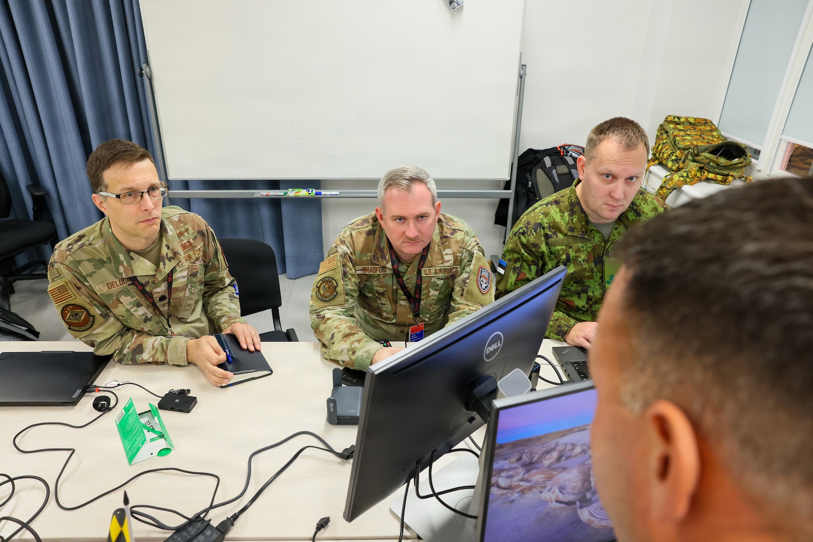 Maryland Air National Guard Lt. Col. Bob DeLuca, flight commander for the 175th Cyberspace Operations Squadron; Capt. James Bradford with the 276th Cyberspace Operations Squadron; and a member of the Estonian Defence Force speak with Maryland Air National Guard Senior Master Sgt. Martin Bartkowski, 275th Operations Support Squadron senior enlisted leader, while they participate in Crossed Swords 25 in Tallinn, Estonia, Nov. 3, 2025.
