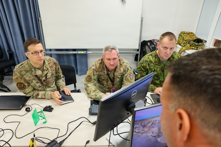 Maryland Air National Guard Lt. Col. Bob DeLuca, flight commander for the 175th Cyberspace Operations Squadron; Capt. James Bradford with the 276th Cyberspace Operations Squadron; and a member of the Estonian Defence Force speak with Maryland Air National Guard Senior Master Sgt. Martin Bartkowski, 275th Operations Support Squadron senior enlisted leader, while they participate in Crossed Swords 25 in Tallinn, Estonia, Nov. 3, 2025.