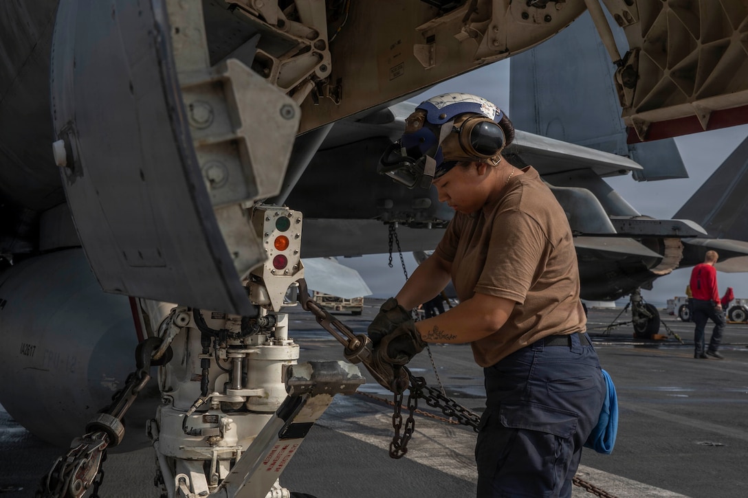 U.S. Navy Aviation Boatswain’s Mate (Handling) Airman Angelica Ramirez removes chains from an F/A-18F Super Hornet, attached to Strike Fighter Squadron (VFA) 41, on the flight deck of Nimitz-class aircraft carrier USS Abraham Lincoln (CVN 72) in the Arabian Sea, Feb. 4, 2026. Abraham Lincoln is deployed to the U.S. 5th Fleet area of operations to support maritime security and stability in the U.S. Central Command area of responsibility. (U.S. Navy photo by Mass Communication Specialist Seaman Apprentice Cesar Zavala)