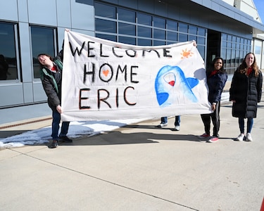 Josiah Karnuth and Nina Harris hold a sign welcoming home their brother, Sgt. Eric Karnuth, from a deployment to the Middle East.